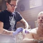 Фотография процесса нанесения татуировки: мастер в перчатках работает над рисунком на теле клиента.