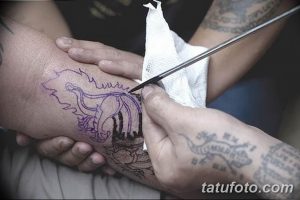 Фотография процесса нанесения эскиза татуировки на кожу клиента. Видна рука мастера с маркером и рука клиента.