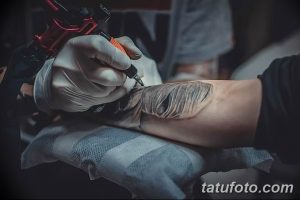 Фото тату процесса нанесения татуировки. Видна рука мастера в перчатке, тату-машинка и кожа клиента с прорисованными деталями.