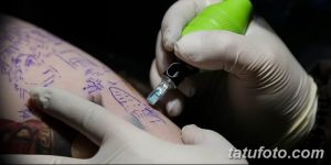 Фото тату процесса нанесения татуировки. Крупный план руки клиента с начальным этапом татуировки и руки мастера с тату-аппаратом.