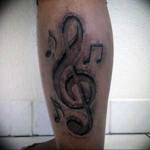 Фото тату на икре: стилизованный скрипичный ключ, выполненный в технике blackwork. Лаконичный и выразительный рисунок татуировки.