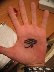 Фото тату: стилизованное изображение Глаза Ра на ладони. Черно-белый рисунок татуировки с четкими линиями.