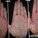 Фото тату на ладони: сложный геометрический рисунок, создающий эффект оптической иллюзии, выполненный в черном и красном цветах.