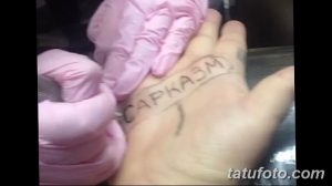 Фото тату с надписью 'Сарказм' на ладони. Черно-белый рисунок татуировки, выполненный простым шрифтом.