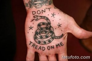 Фото тату змеи на ладони с надписью 'Don't Tread on Me'. Черно-белый рисунок татуировки в стиле традиционной американки.