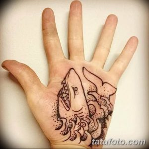 Фото тату: Изображение акулы на ладони. Детализированный рисунок татуировки с использованием черных линий и точек. Подходит для любителей морской тематики.