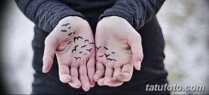 Фотография татуировки с изображением силуэтов летучих мышей на обеих ладонях. Черно-белый рисунок с минималистичным дизайном.