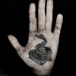 Фото тату: изображение глаза, обвитого змеей, на ладони руки. Черно-белая татуировка с высокой детализацией и мистическим символизмом.