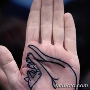 Фото тату на ладони: силуэт птицы в полете, выполненный черными линиями. Простой и элегантный рисунок татуировки.
