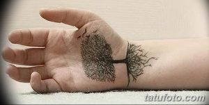 Фото тату: Изящное изображение дерева, выполненное тонкими линиями на ладони руки. Черно-белый рисунок татуировки выглядит очень органично.