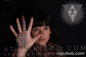 Фото тату: татуировка в стиле трайбл, выполненная на тыльной стороне руки, с использованием черных линий и завитков.