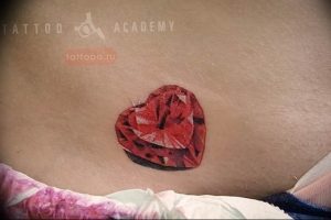 Фото тату рубинового сердца на спине. Простой и элегантный рисунок татуировки в красных тонах.