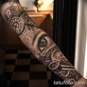 Фото тату на всю руку с изображением карманных часов, глаза и цифр. Черно-серый рисунок татуировки в реалистичном стиле.