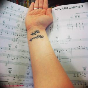 Фото тату на запястье: изящная надпись "Forever" каллиграфическим шрифтом, выполненная в черном цвете, символизирующая вечность и преданность.