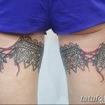 Фото тату на бедрах: симметричные кружевные пояса с ниспадающими лентами, выполненные в черно-серых тонах, с реалистичными деталями.
