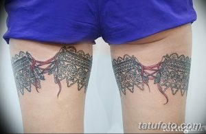 Фото тату на бедрах: симметричные кружевные пояса с ниспадающими лентами, выполненные в черно-серых тонах, с реалистичными деталями.