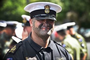 Фото традиционной маорийской татуировки на лице военнослужащего. Рисунок выполнен черными чернилами в сложной геометрической форме.