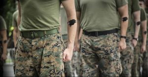 Группа военных в камуфляжной форме с татуировками кабаньей головы на предплечьях. Фотография сделана на фоне зелени.