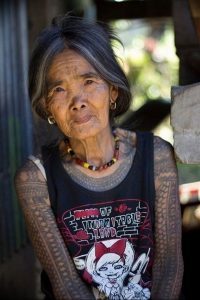 Фотография пожилой женщины с традиционными татуировками на лице, демонстрирующая культурные обычаи и ритуалы.