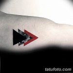 Фото тату: абстрактная геометрическая татуировка из черных и красных треугольников на руке. Современный и стильный рисунок.