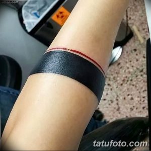 Фото тату: минималистичный браслет на руке, выполненный в черном цвете с тонкой красной линией.