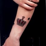 Фото тату: изящная корона с драгоценными камнями и маленькая звезда на женском запястье. Идеальный рисунок татуировки для тех, кто ценит роскошь и индивидуальность.