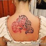 Фото тату двух лошадей на спине. Одна голова черная, другая красная, выполнены в стиле трайбл с использованием завитков и узоров.