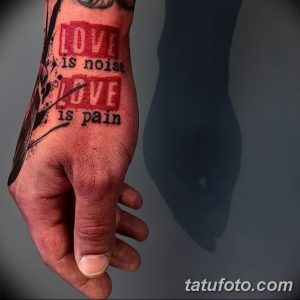 Фото тату с надписью "Love is noise, Love is pain" на руке. Минималистичный стиль, черные чернила, немного размытый эффект.