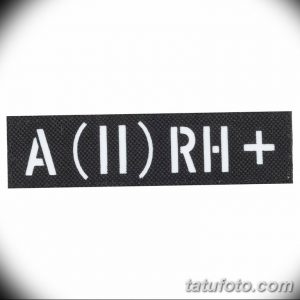 Фотография минималистичной татуировки с изображением группы крови A (II) RH+. Черные буквы на белом фоне, четкий и лаконичный дизайн.
