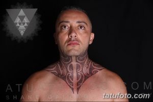 Фото татуировки в стиле трайбл на шее и груди мужчины. Черный рисунок с геометрическими формами и острыми углами. Мужественный и впечатляющий дизайн.
