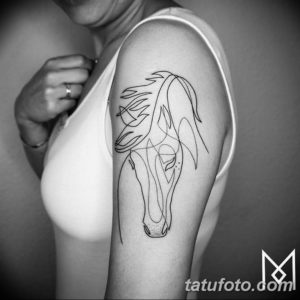 Фото минималистичной татуировки лошади, выполненной в стиле line art на плече. Рисунок состоит из тонких, непрерывных линий, создающих силуэт лошади.
