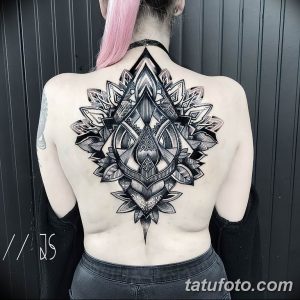 Фото тату: черная мандала с острыми углами и геометрическими формами на спине девушки с розовыми волосами. Детализированный рисунок татуировки.