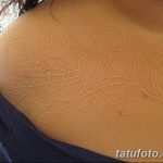Фото белого тату на плече. Нежный растительный узор с листьями и цветами, выполненный белыми чернилами.
