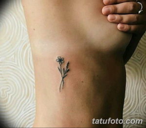 Фотография маленькой татуировки с изображением цветка и листьев на запястье. Изящный рисунок в стиле лайнуорк.
