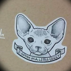 Черно-белое фото тату сфинкса с закрученными зрачками и надписью "ESPHINX I'M A LITTLE DIZZY". Изображение выполнено в стиле олдскул.