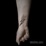Фото минималистичной татуировки на запястье: череп, пронзенный молнией. Простой и символичный рисунок татуировки.