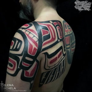 Фото тату на спине: большая татуировка в стиле Northwest Coast Native с изображением тотемных животных и геометрических узоров. Черно-красный рисунок татуировки.