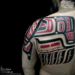 Фото тату на плече: татуировка в стиле Northwest Coast Native с изображением тотемного животного и геометрических узоров. Черно-красный рисунок татуировки.