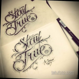 Фото эскиза татуировки с надписью 'Stay True', выполненной в стиле Old School с использованием черных контуров и традиционных элементов.