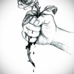 Черно-белый эскиз татуировки с изображением руки, сжимающей розу. Символичное и эмоциональное изображение.