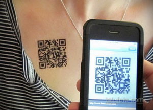 Фото татуировки QR-кода на груди женщины. Смартфон сканирует код, отображая ссылку на веб-сайт.