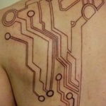 Фото тату: Сложная биомеханическая татуировка, имитирующая электронные схемы на плече и груди. Детализированный рисунок татуировки.