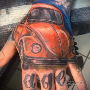 Фото татуировки в виде оранжевого Volkswagen Beetle на руке. Детализированный рисунок с использованием ярких цветов и теней.