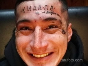 Фото мужчины с татуировкой на лице. Надпись 'КИАЛА' и символ, выполненные черным цветом. Экстремальный и вызывающий образ.