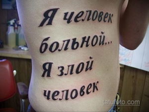 Фото татуировки с надписью 'Я человек больной... Я злой человек' на боку. Простой, но вызывающий рисунок татуировки, выполненный черными чернилами.