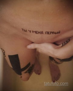 Фото тату надписи "ты у меня первый" на животе. Рисунок выполнен тонкой линией черного цвета, выглядит нежно и интимно.
