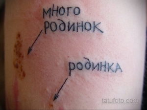 Фото тату на руке, изображающее родинки с подписями "много родинок" и "родинка". Татуировка выглядит иронично.