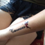 Фото тату: Небольшая татуировка на предплечье с надписью 'Tawneet' и изображением силуэта птицы, выполненная в черном цвете.