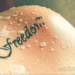 Фото татуировки с надписью 'Freedom' выполненной черными чернилами на коже. Простой и лаконичный рисунок.