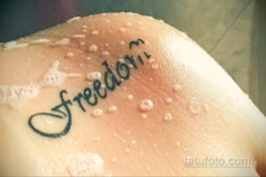 Фото татуировки с надписью 'Freedom' выполненной черными чернилами на коже. Простой и лаконичный рисунок.